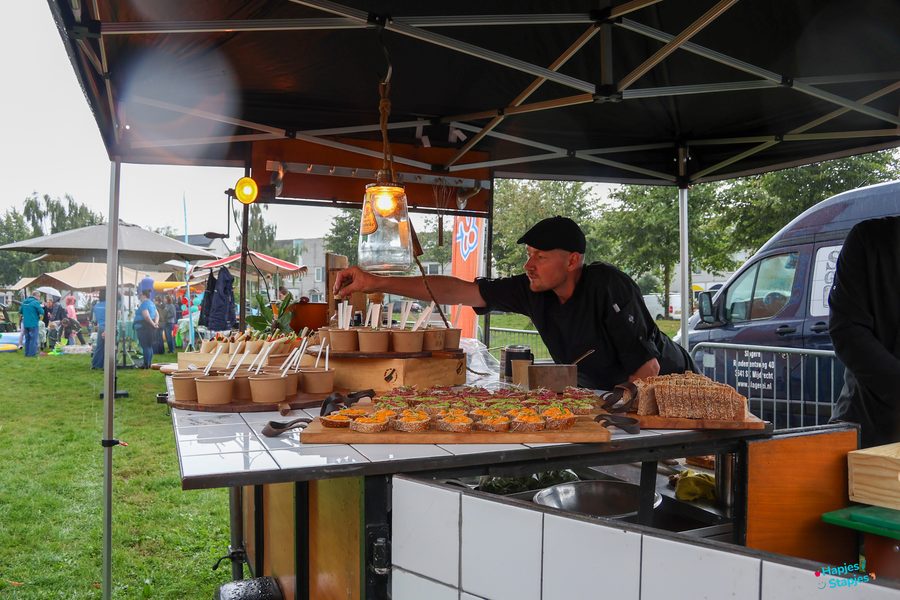 Kok achter een foodtruck maakt hapjes klaar op een houten plank