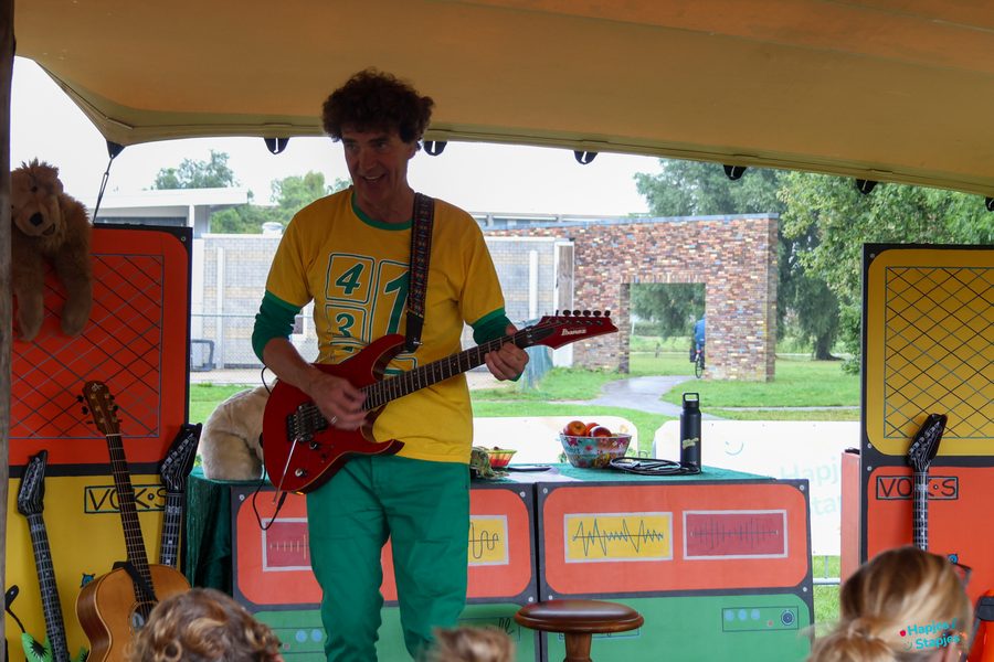 Dirk Scheele met rode gitaar geeft een kindervoorstelling in de tent