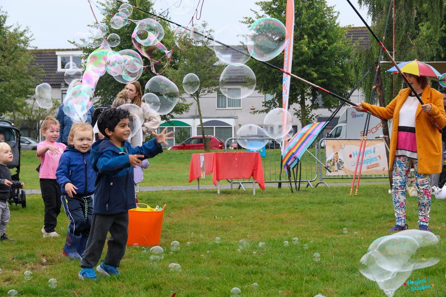 Groepje kinderen rent achter zeepbellen aan in het park