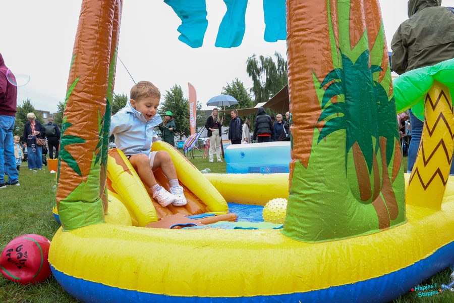 Kleuter glijdt van een klein opblaasglijbaantje het water in